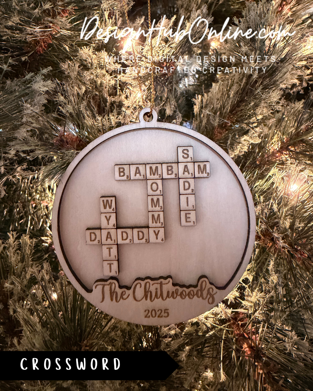 A wooden ornament hanging on a Christmas tree, featuring a crossword puzzle with the letters B, A, M, B, O, M, D, E, I, W, Y, D, A, D, Y, T, and the text "The Chitwoods" and "Crossword" printed on it.