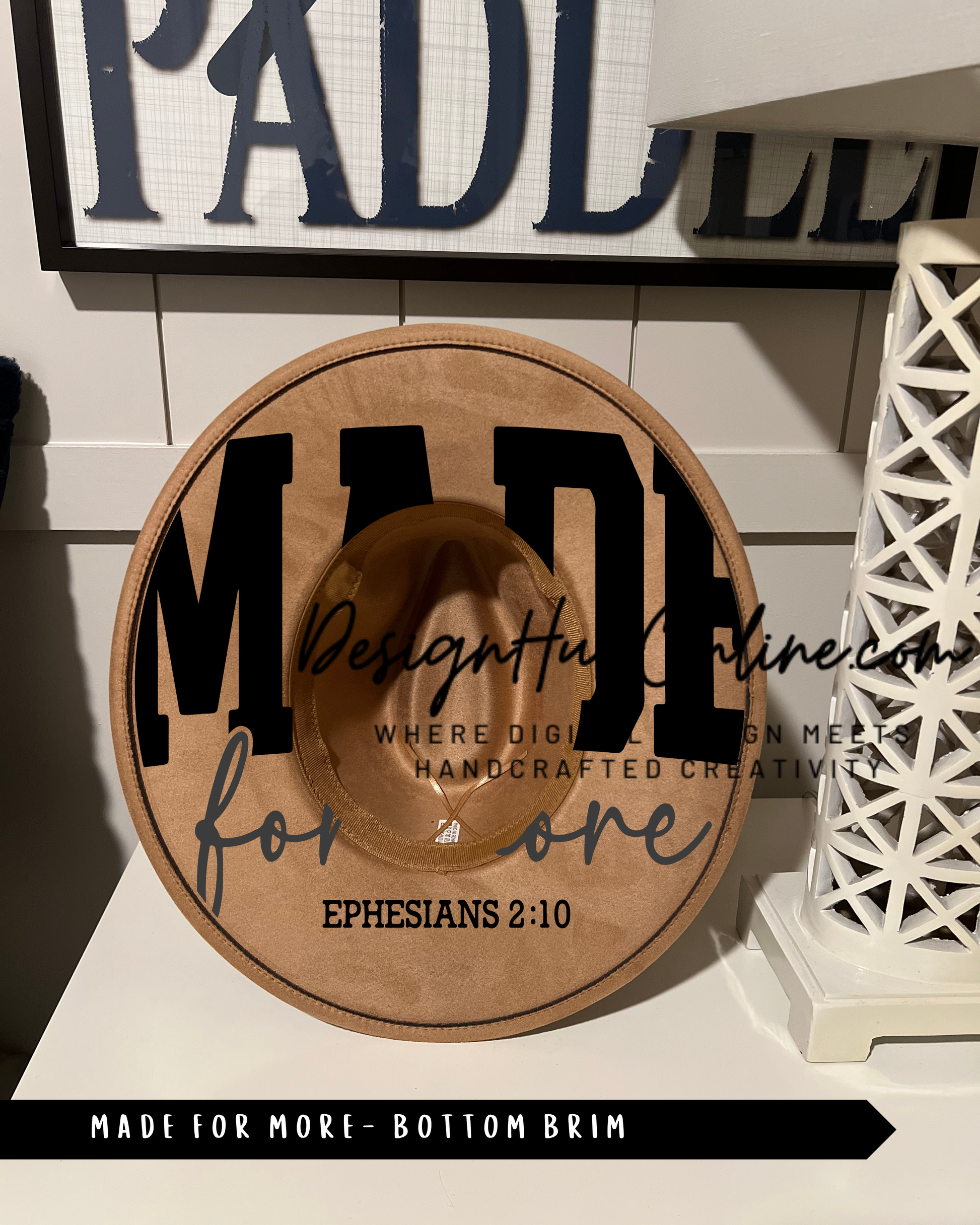 a wooden hat with the word "MADE" printed on it, along with the text "Designful Online" and "Where Digitally Crafted Creativity Meets" printed below. The hat is placed on a white surface, and there is a sign with the word "PADDLE" visible in the background.