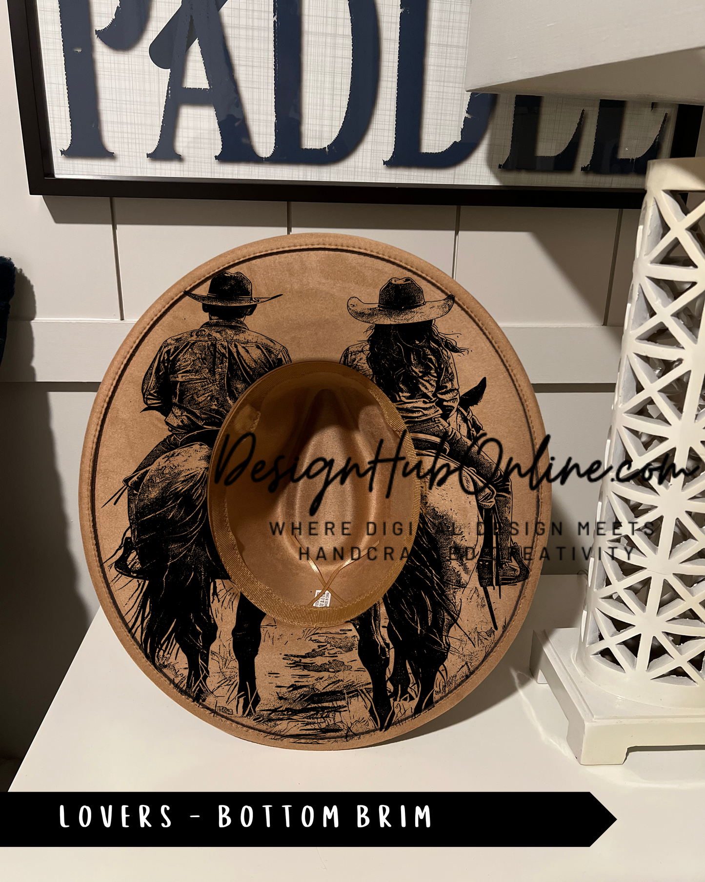 A wooden hat with a design of two people riding horses, placed on a white surface.