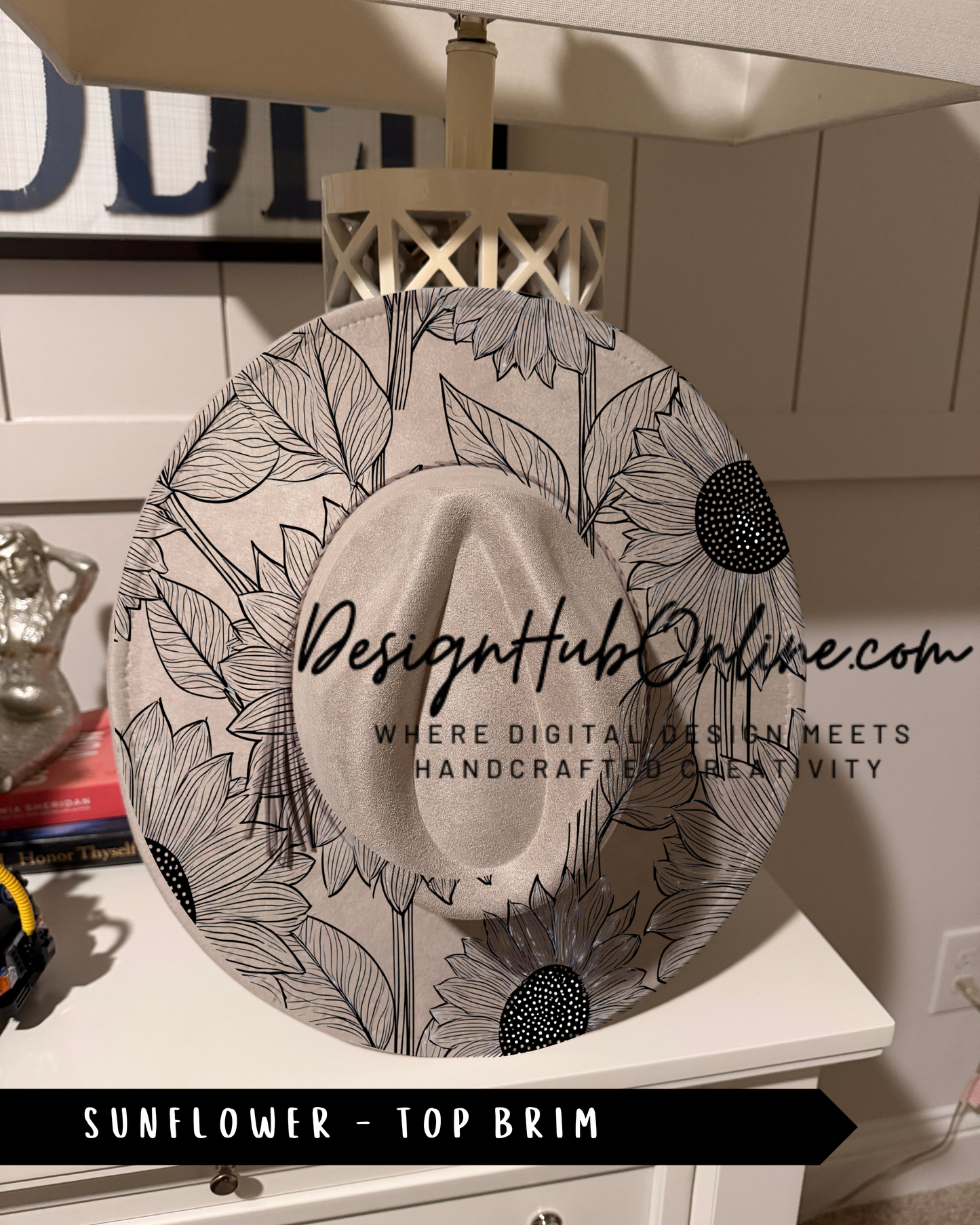 A white hat with a black and white floral pattern, placed on a white dresser.