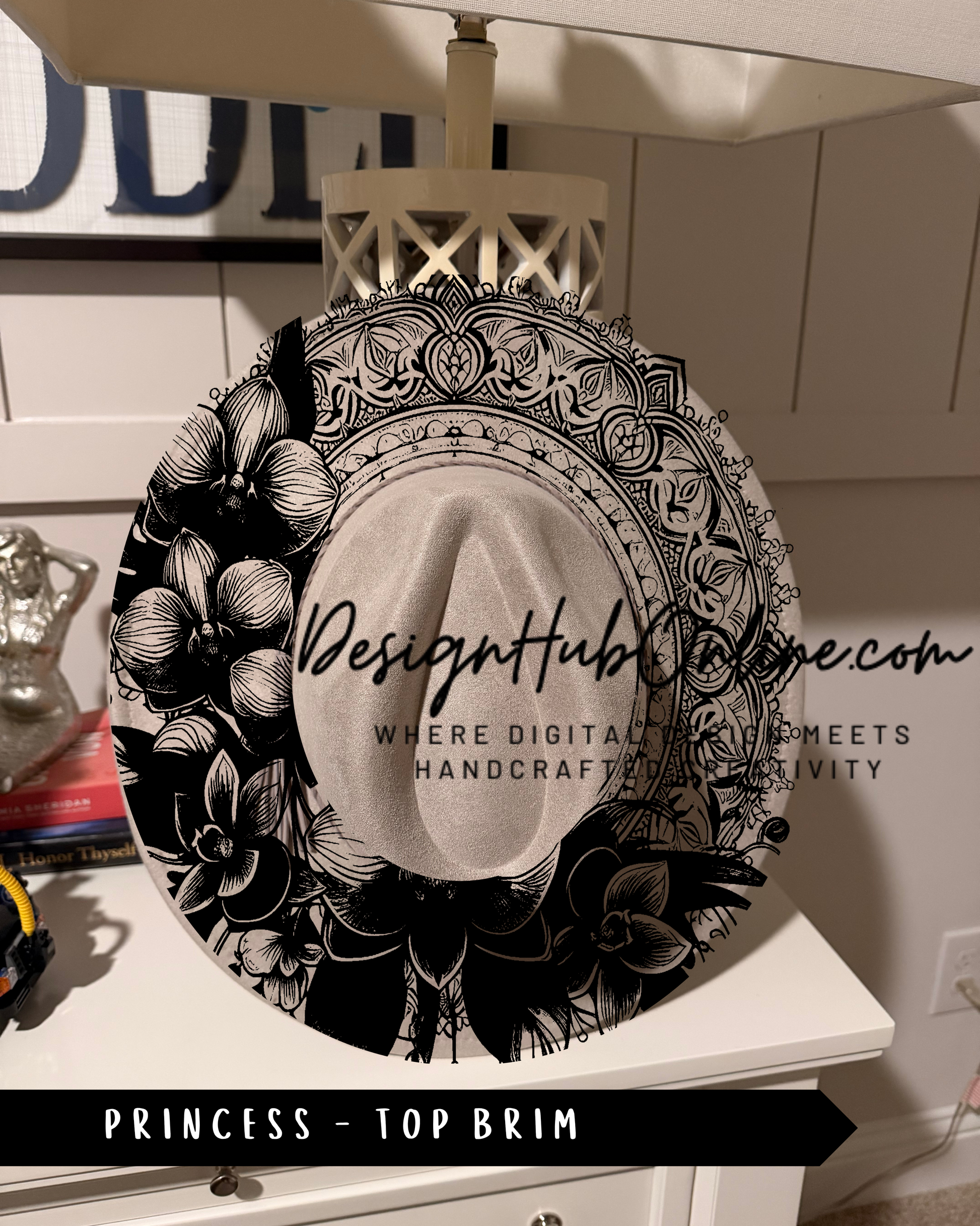 A decorative black and white hat with floral and geometric patterns, placed on a white surface.