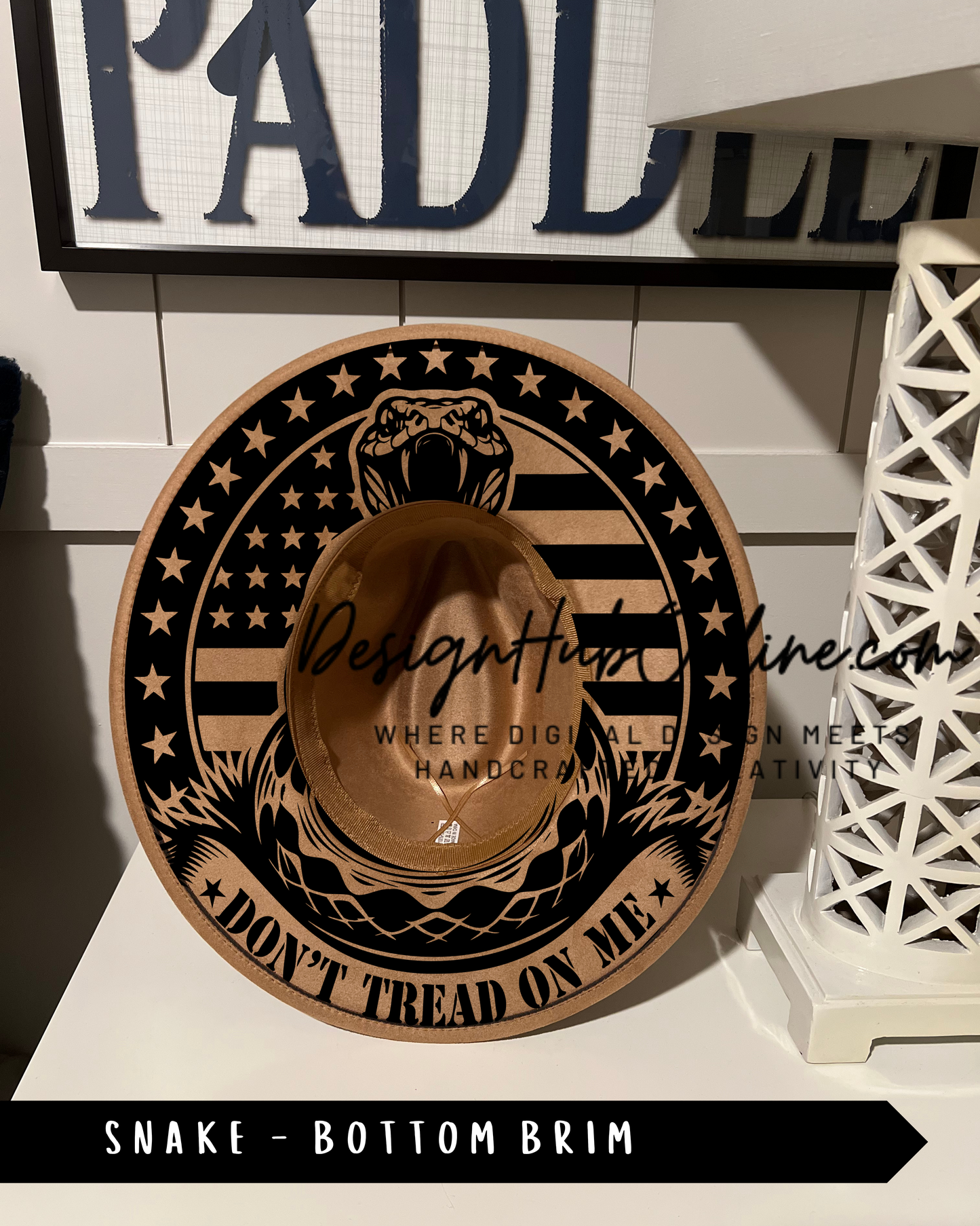 A hat with a snake design and the text "Don't Tread on Me" printed on it, displayed on a shelf.