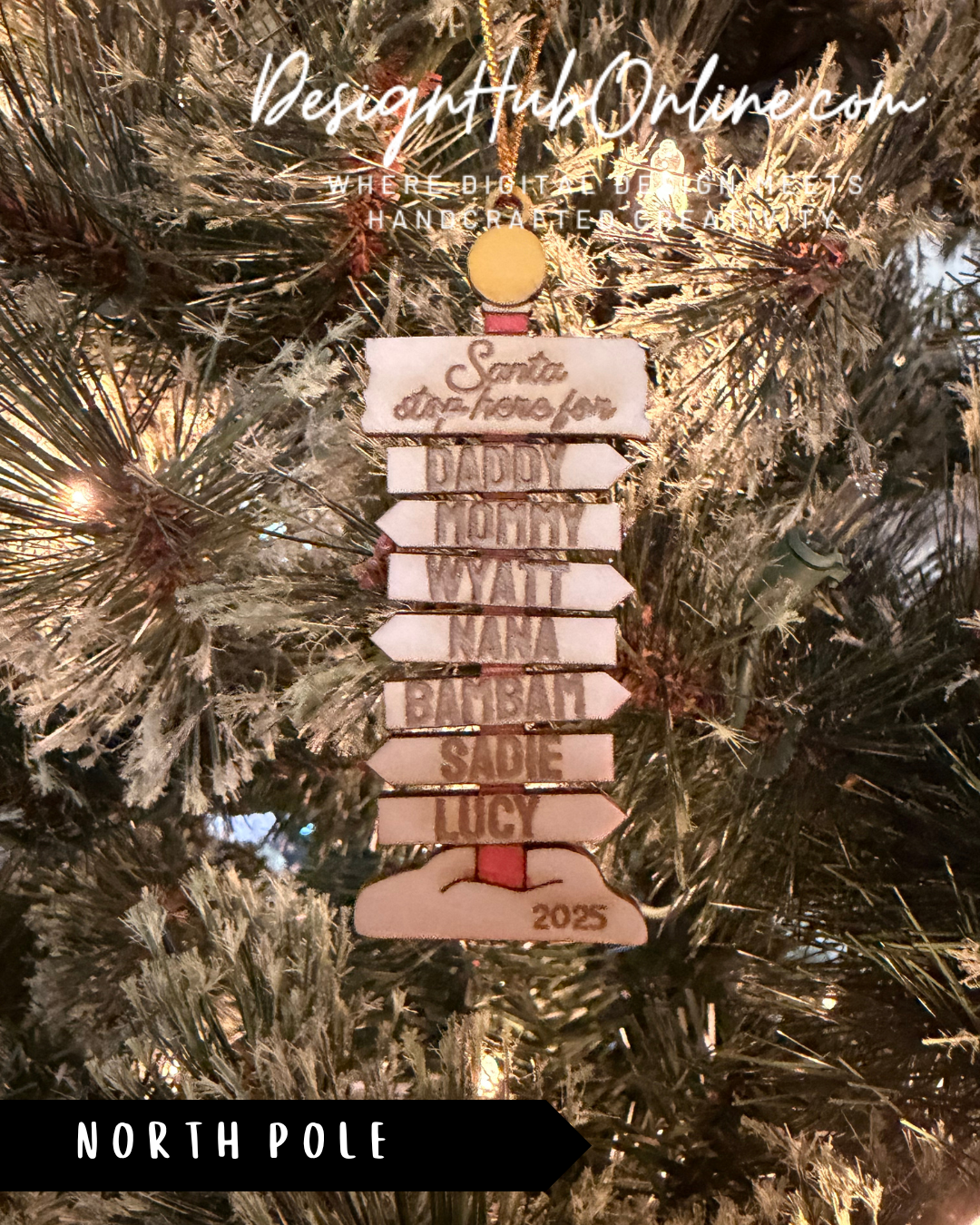 A Christmas ornament with a directional sign hanging on a tree, displaying the names of various relatives or family members.