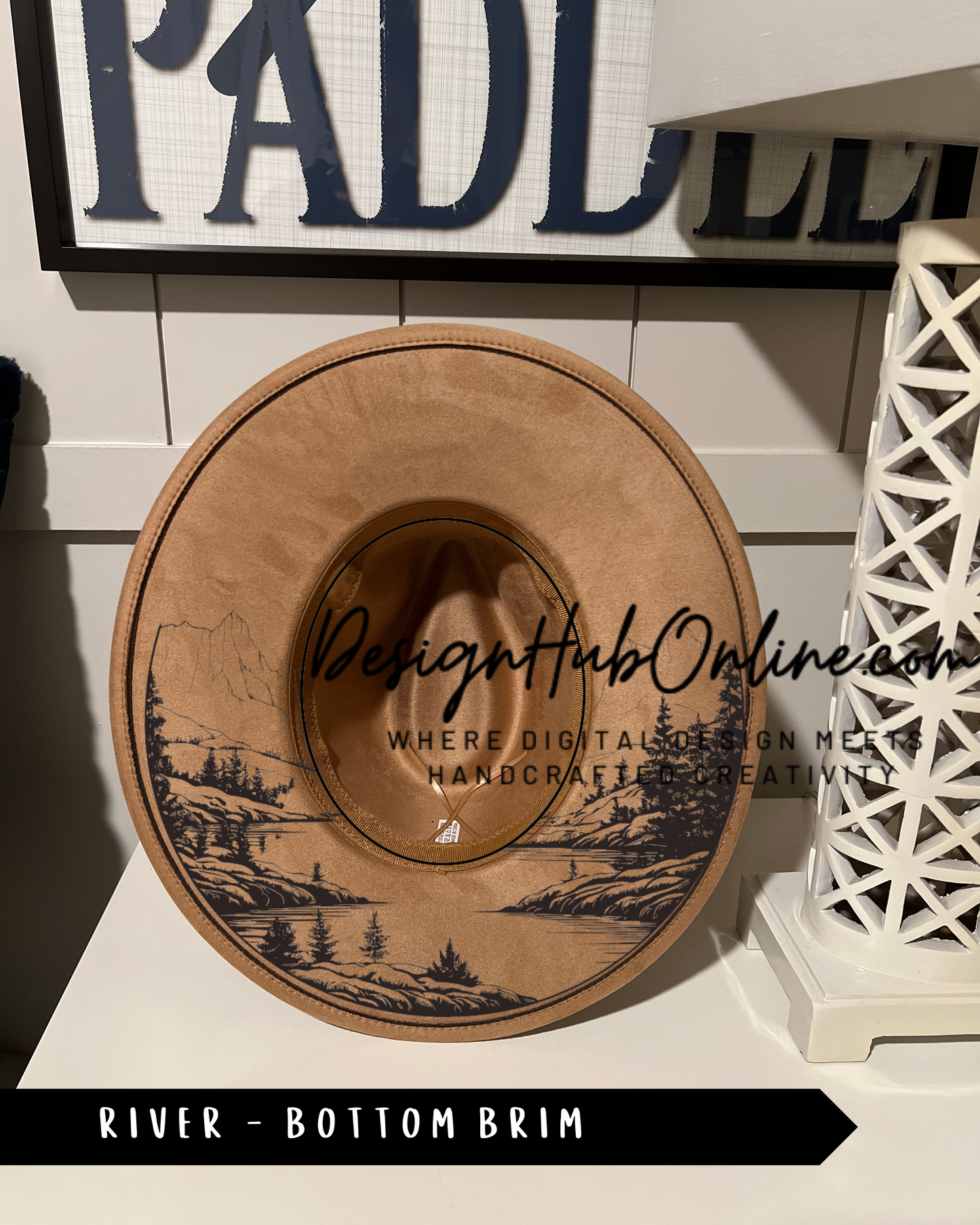 A wooden hat with a landscape design on it, placed on a white surface.