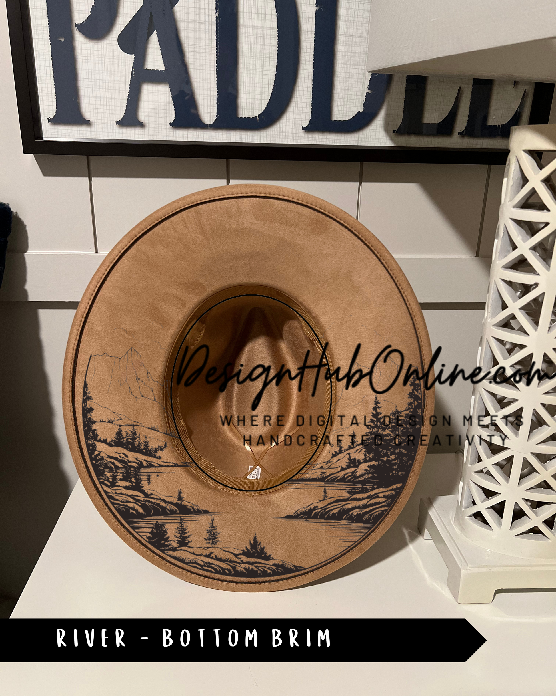 A wooden hat with a landscape design on it, placed on a white surface.