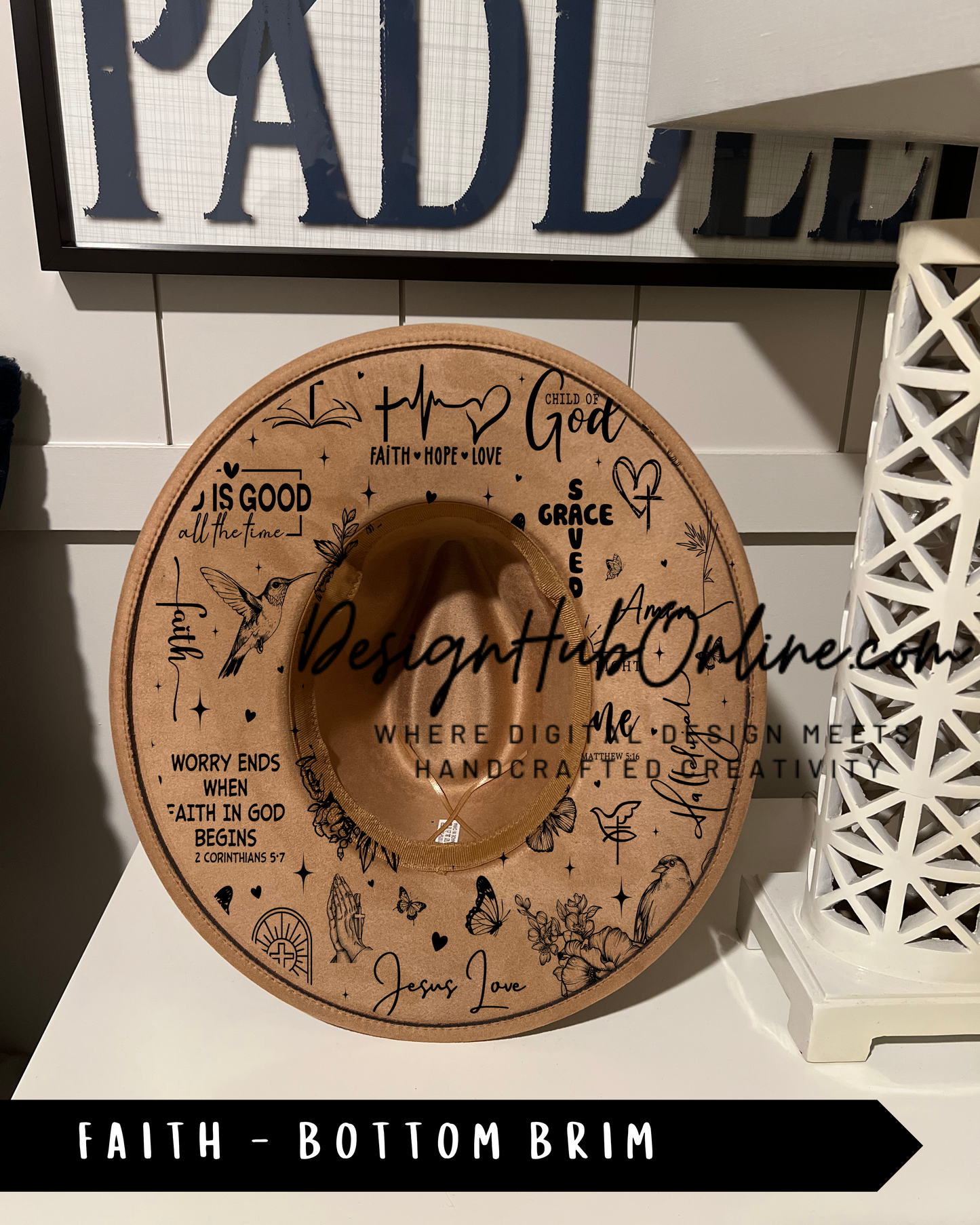 A wooden hat with various religious and inspirational sayings and symbols printed on it, placed on a white surface.