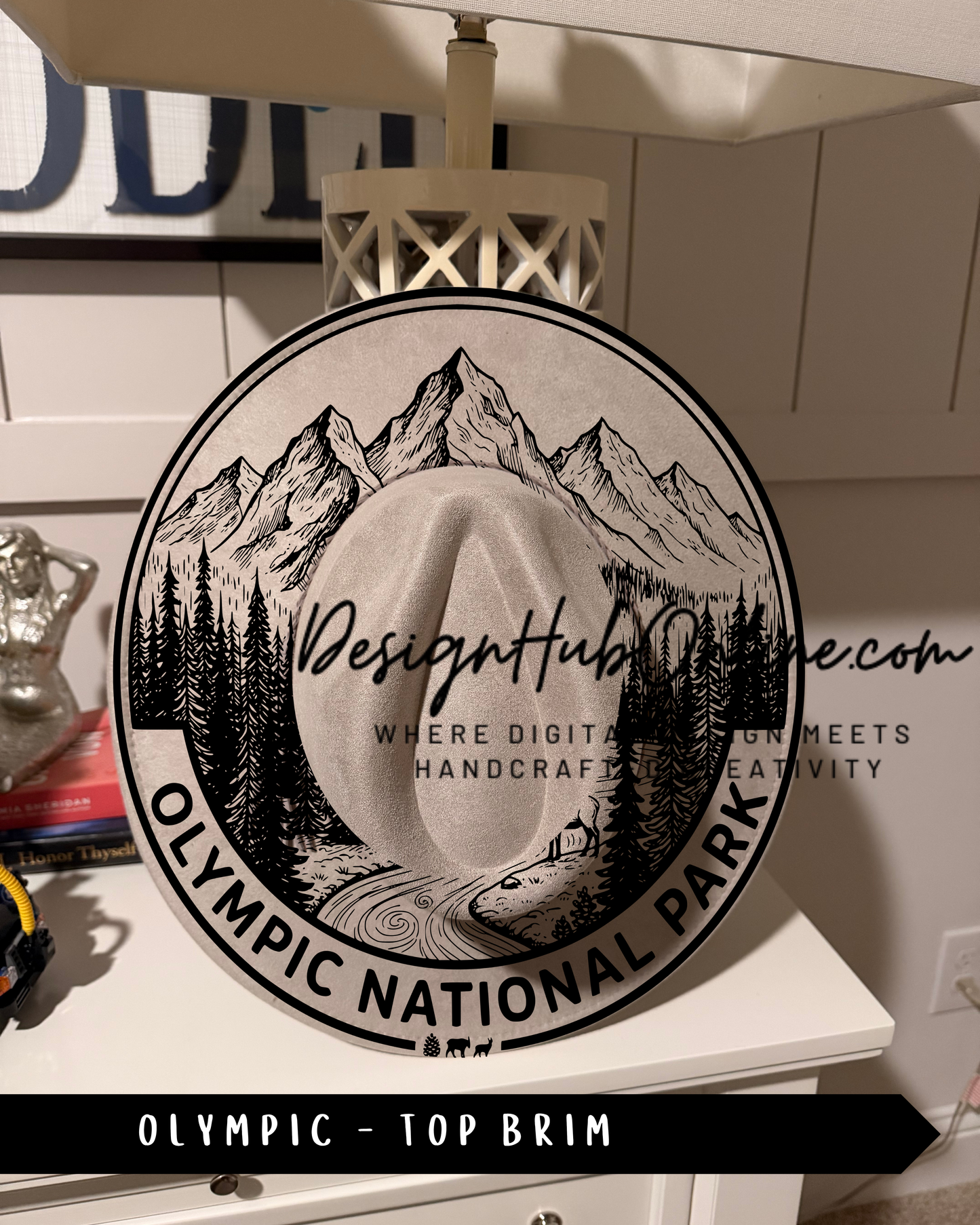 a decorative sign for the Olympic National Park, with a mountain landscape and a cowboy hat in the center.