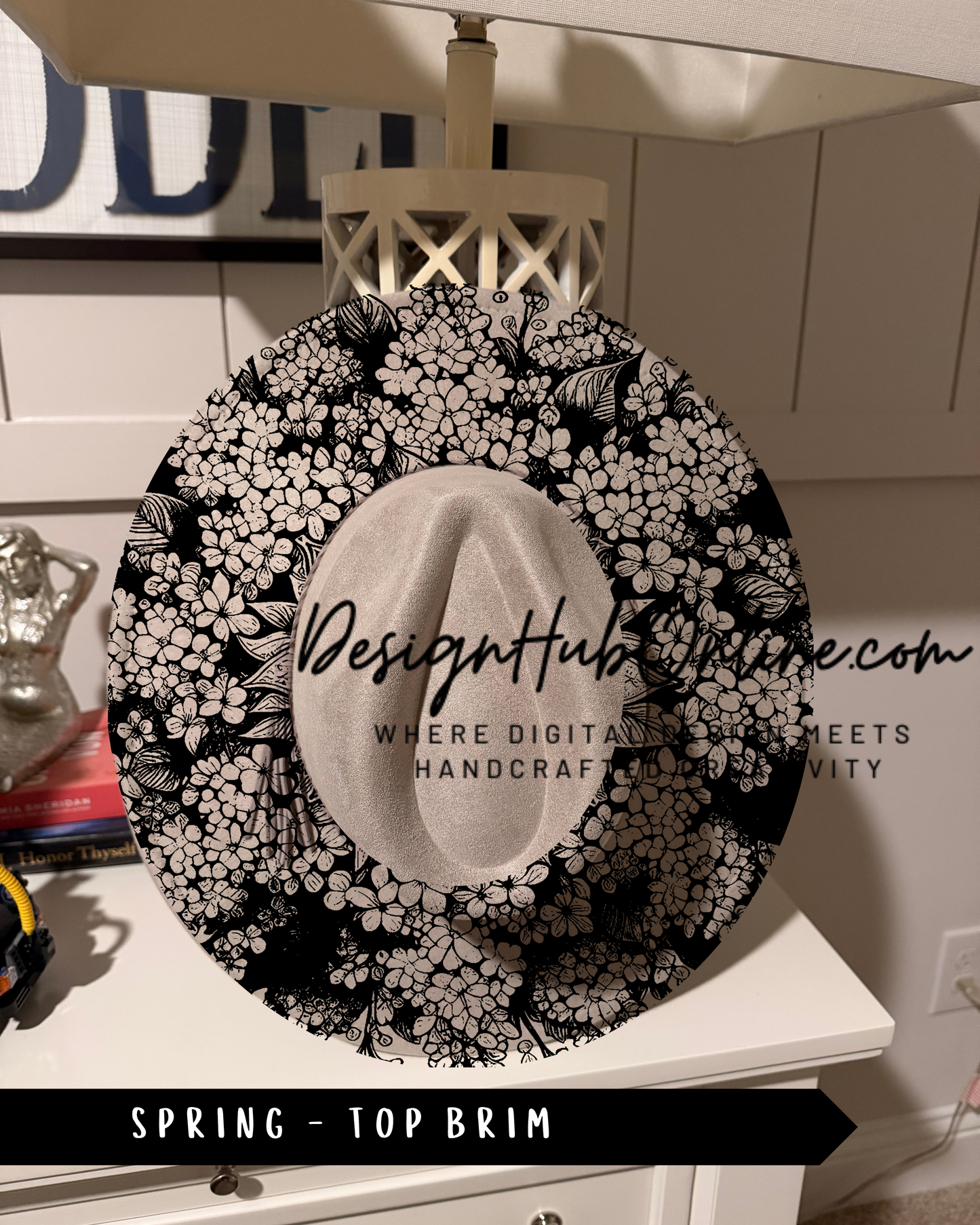 A decorative black and white floral pattern on a hat, with the text "Design Hub" and "Spring - Top Brim" printed on it.