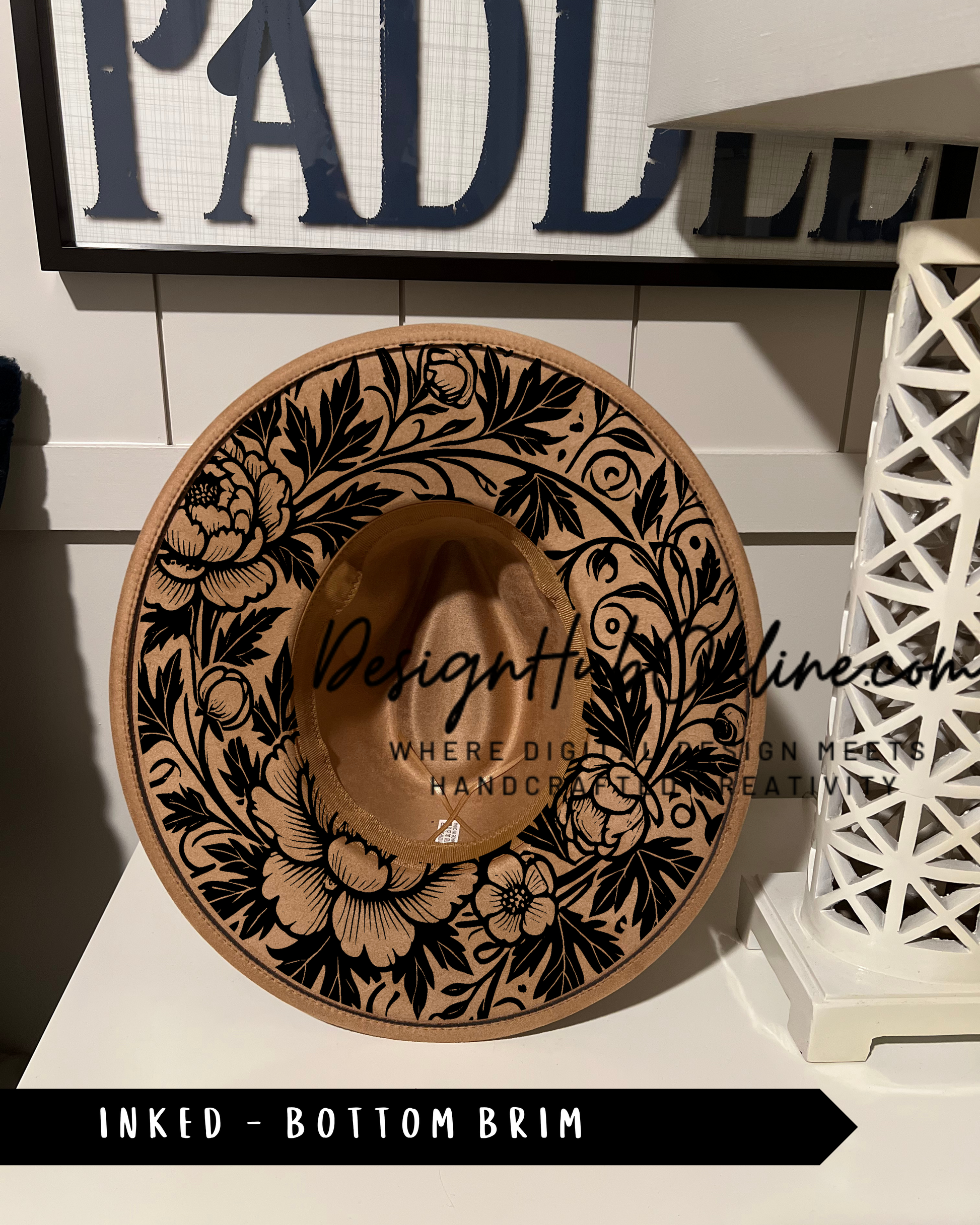 A decorative hat with a floral pattern and the text "DesignHine.com" printed on it, placed on a white surface.
