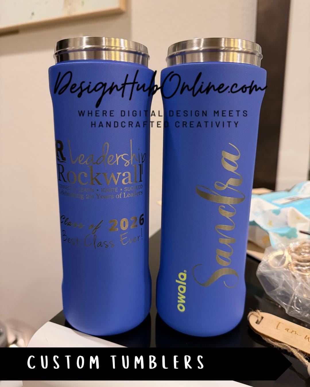 Two custom blue tumblers with personalized names and designs, placed on a table.