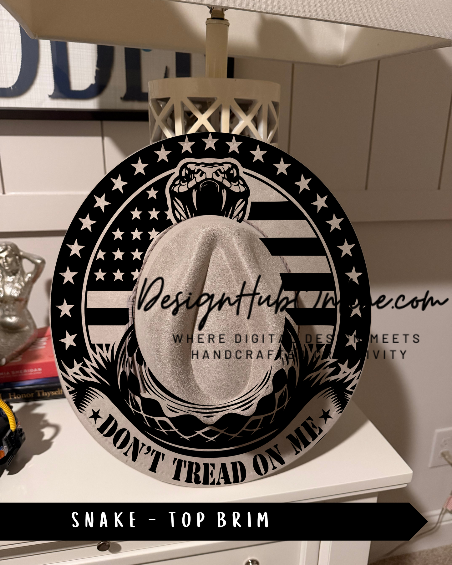 A black and white image of a hat with a snake design, featuring the text "Don't Tread on Me" and "Top Brim" printed on it.