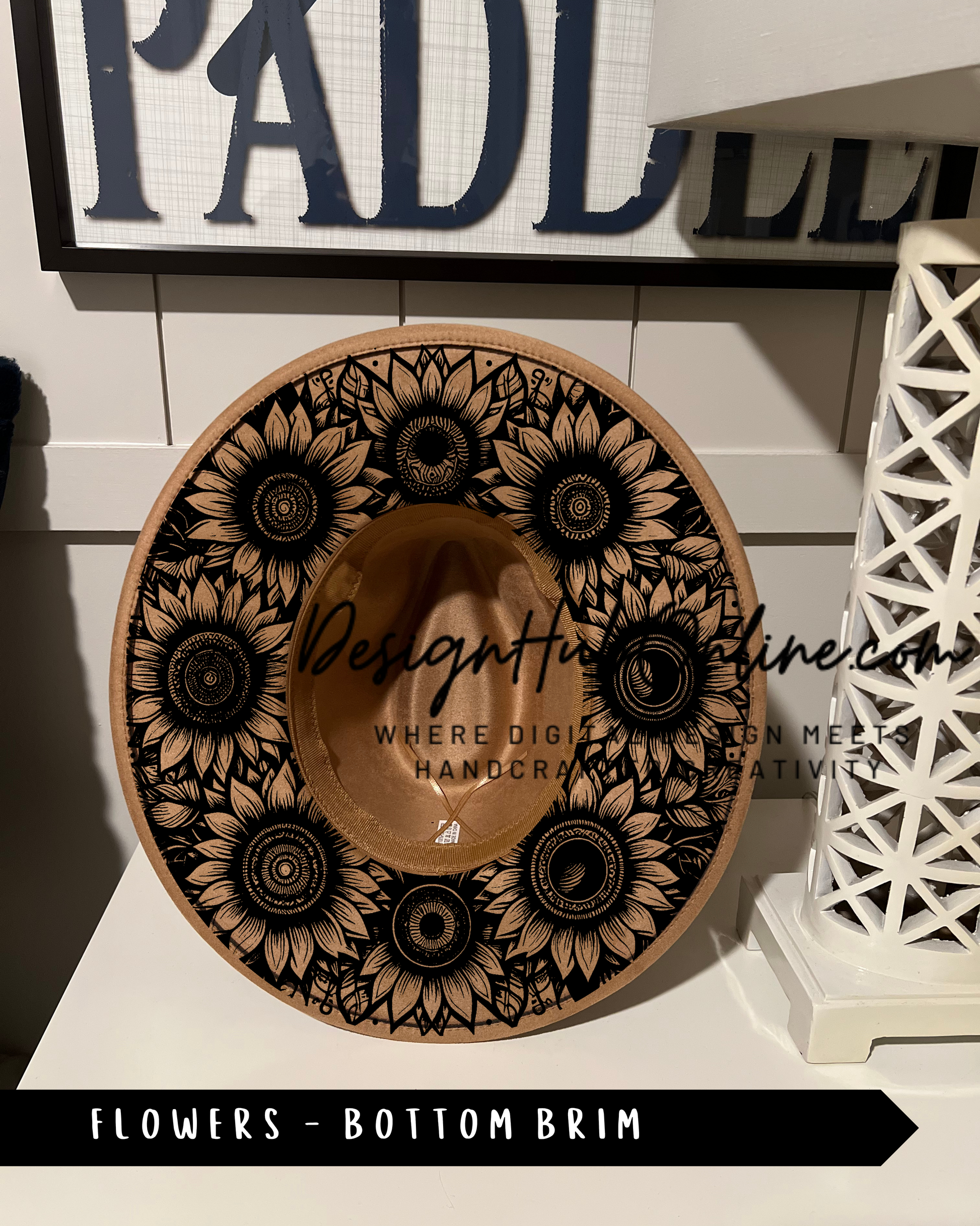 A hat with a sunflower design, placed on a shelf next to a white lamp.