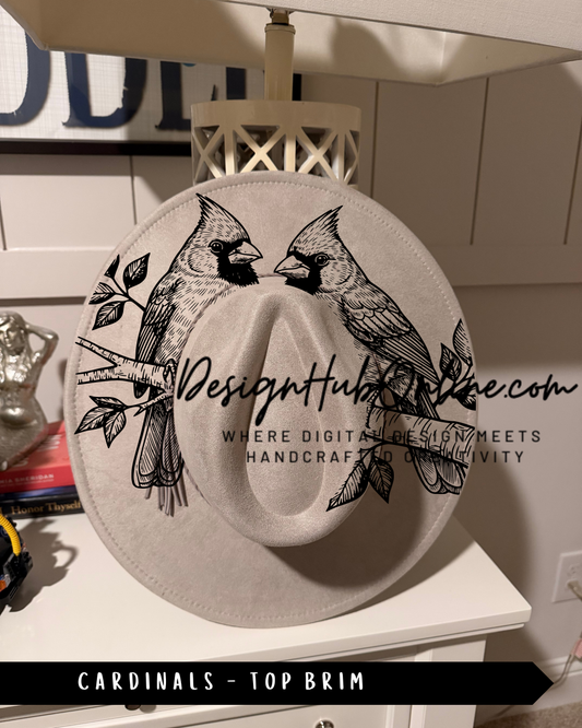 A white hat with a black and white illustration of two cardinals perched on a branch, along with the text "Design Hub" and "Where digital design meets handmade craftsmanship and luxury".