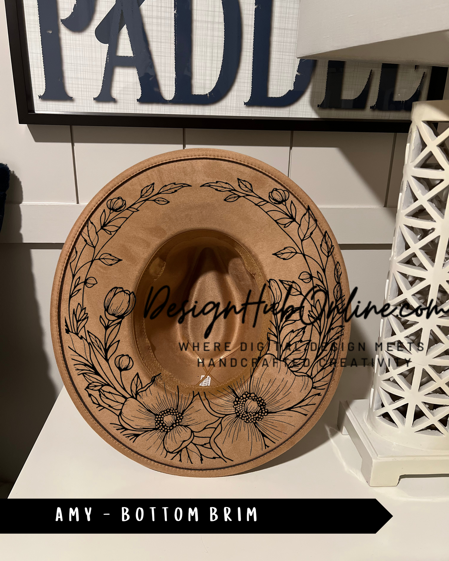 A wooden hat with a floral design on it, placed on a white surface.