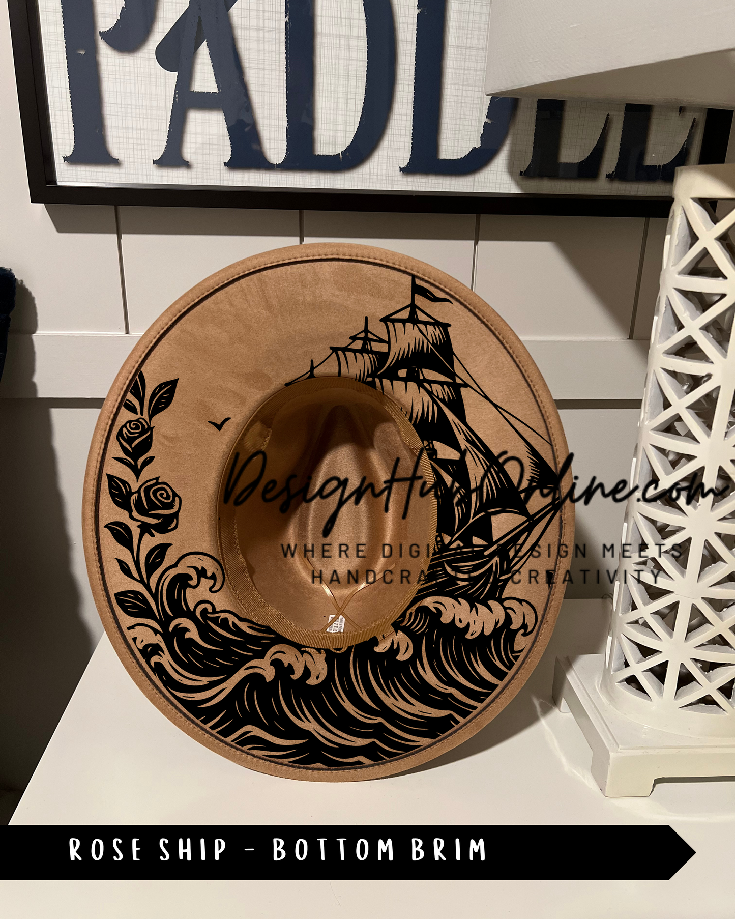 A wooden hat with a ship design on it, placed on a white surface.