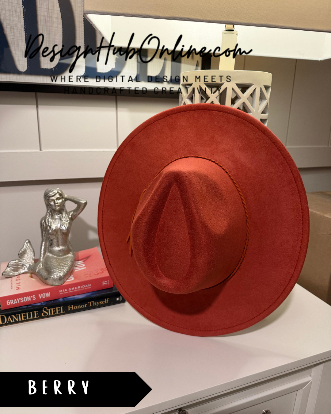 a red hat placed on a white surface, with a mermaid figurine and some books nearby.